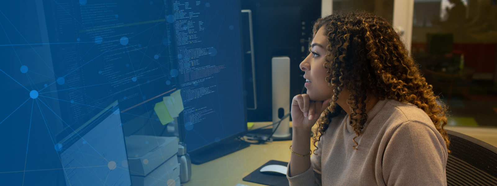 Female developer sitting at a customized workspace with a multi-monitor set up.