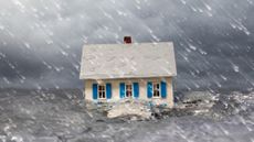 White single family house partially submerged in turbulent water with a stormy sky and wind blown rain