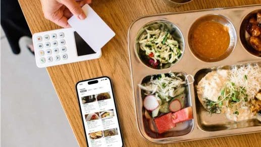 A phone next to a tray of food.