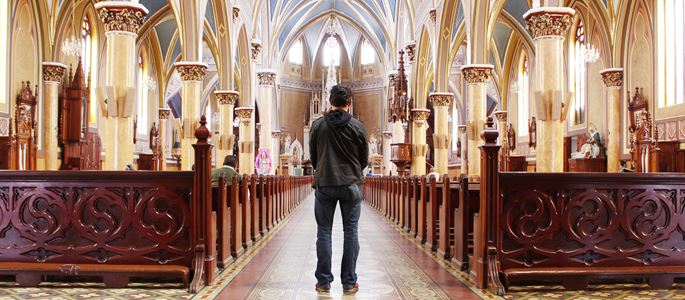 Ein Mann steht im Mittelgang einer Kirche.