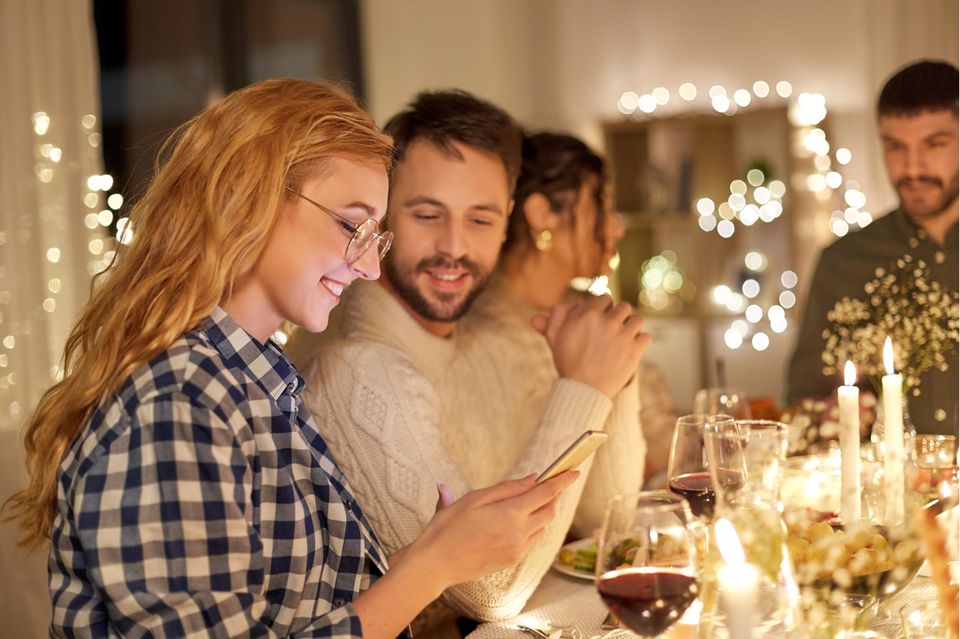 Gruppe von Menschen an weihnachtlich gedecktem Tisch