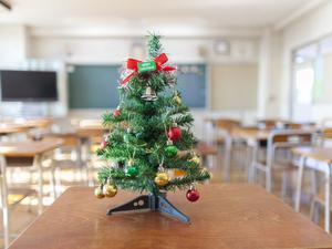 Ein Weihnachtsbaum steht in einem Klassenzimmer.