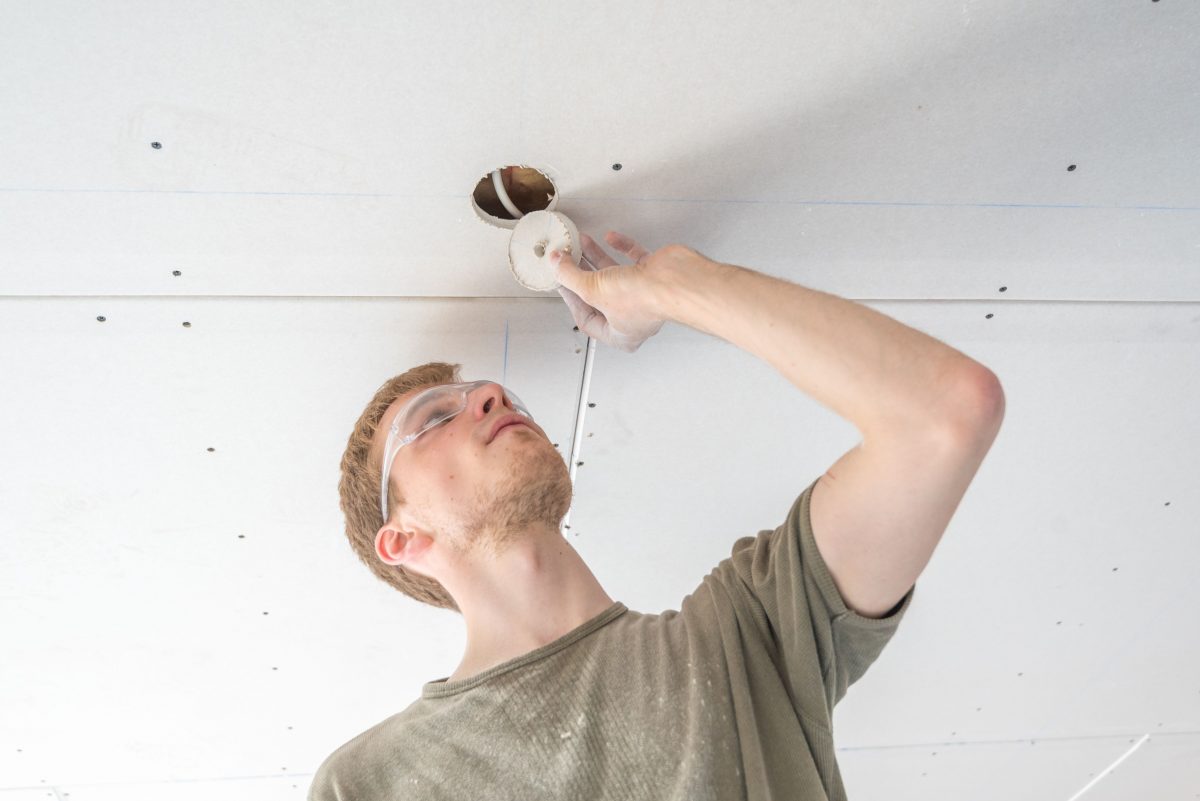 Handwerker bringt Deckenleuchten für den Kellerausbau an.