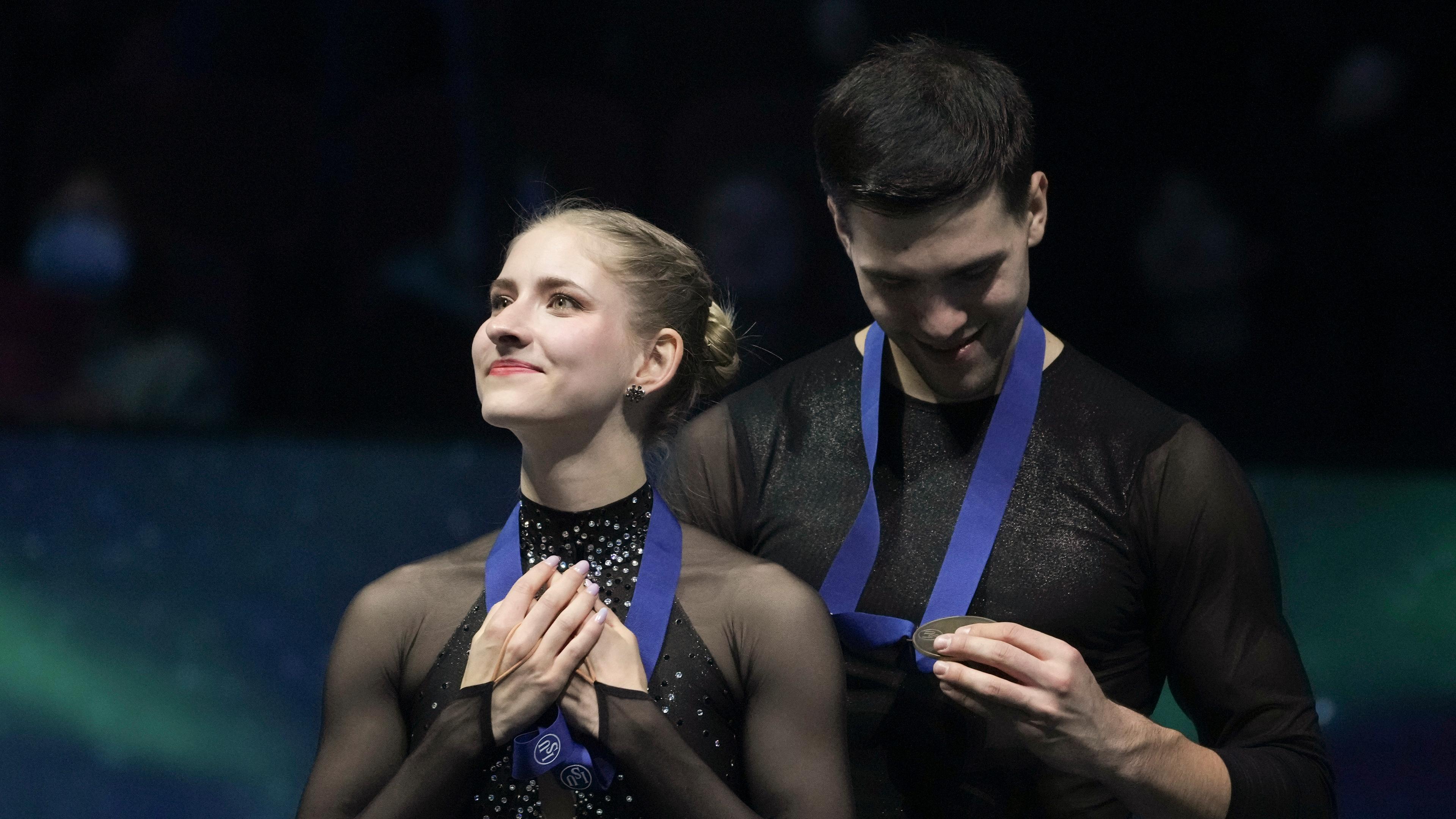 Minerva Fabienne Hase und Nikita Wolodin bei der Siegerehrung. Beide sehen glücklich aus. Sie hat ihre Hände über die Medaille gelegt und er betrachtet seine Medaille.