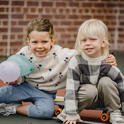 Ein Mädchen und ein Junge auf einem Skateboard draußen