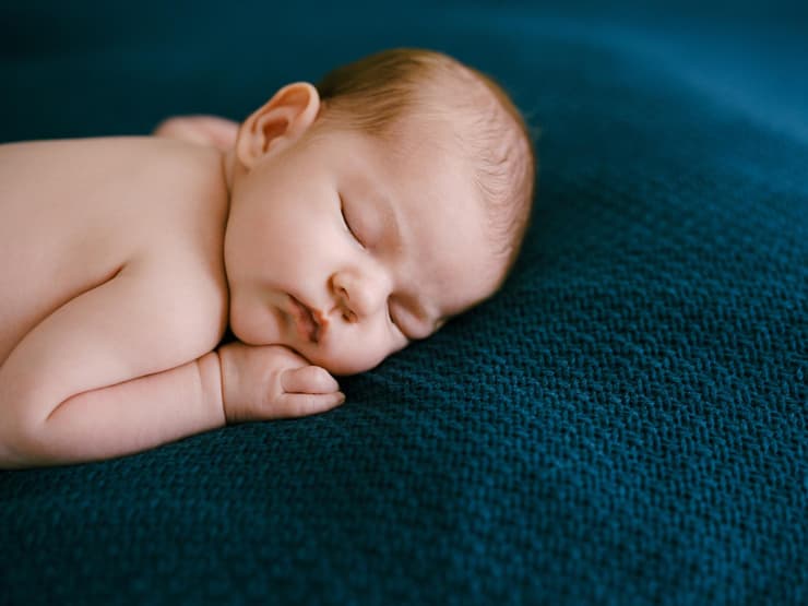 Ein Baby schläft in Bauchlage.