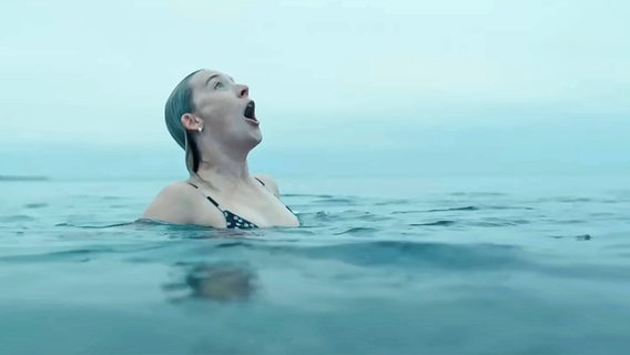 Eine junge Frau schaut erfreut in den Himmel im kalten Wasser des Ozenans - Szene aus dem Drama "The Outrun" © StudioCanal Sony BBC / IMAGO / Landmark Media 