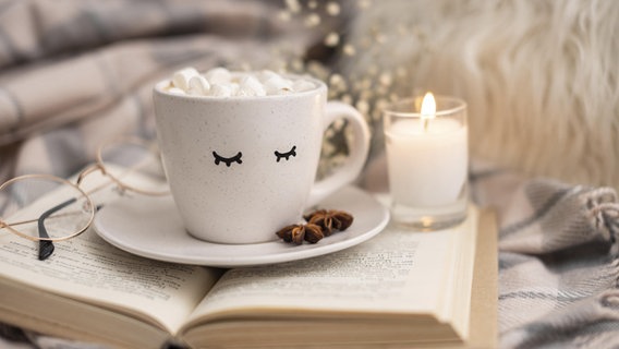 Ein Latte Macchiato, eine Brille und eine Kerze liegen auf einem Buch © picture alliance / Zoonar | Oleksandr Latkun 