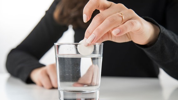 Eine Frau hält eine Brausetablette über einem Wasserglas in der Hand. © picture alliance / dpa Themendienst Foto: picture alliance / dpa Themendienst | Christin Klose