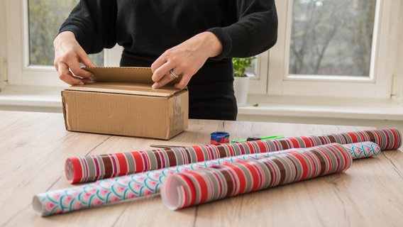 Eine Frau packt ein Geschenk in ein Päckchen. © picture alliance / dpa Themendienst Foto: Christin Klose