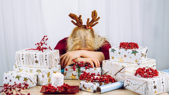 Unerkennbare Hausfrau die es satt hat zu Hause Weihnachtsgeschenke zu verpacken. Stapelweise Geschenke. Konzept für saisonale Feiertage. © panthermedia/ FotoHelin Foto: FotoHelin