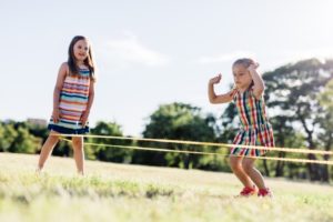 Kinder springen draußen Gummitwist