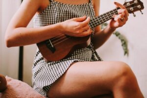 eine sitzende Frau spielt Ukulele auf einem Stuhl