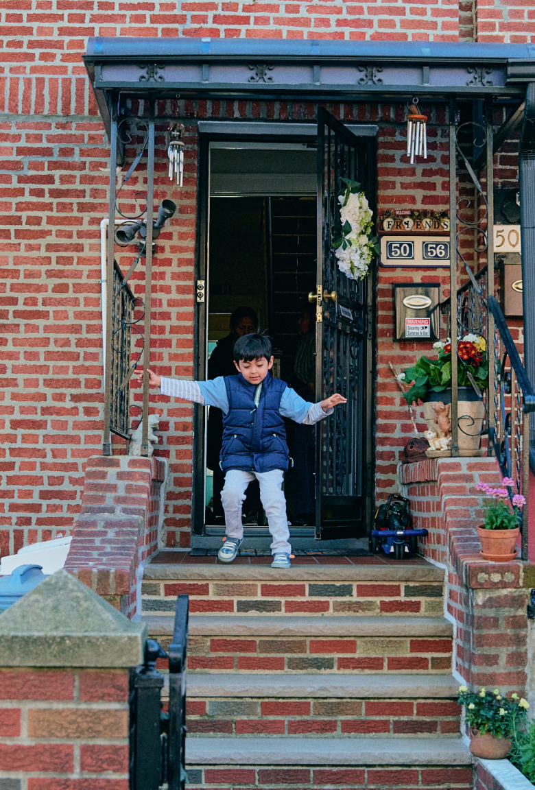 A small child walking down the front steps of a New York brownstone. 