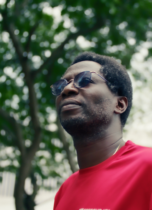  A Ghanaian man in sunglasses and a red shirt.