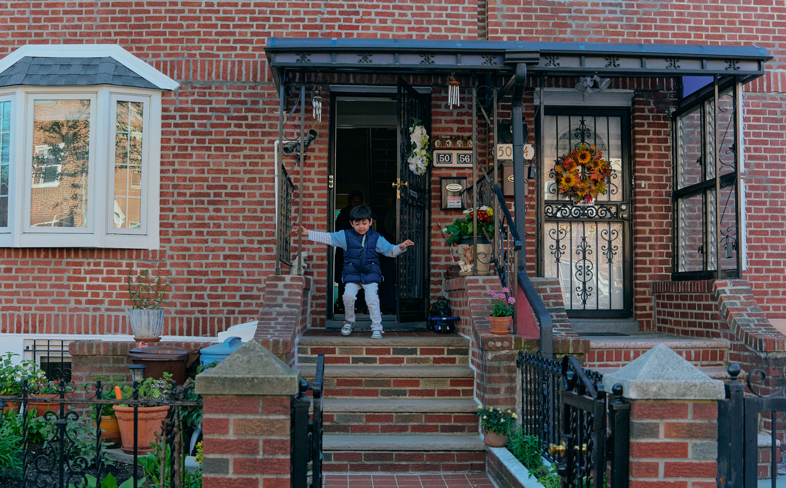 A small child walking down the front steps of a New York brownstone. 