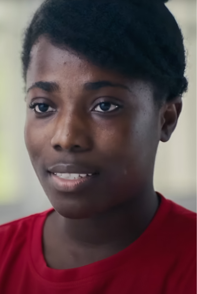 A Ghanaian woman in a red shirt.