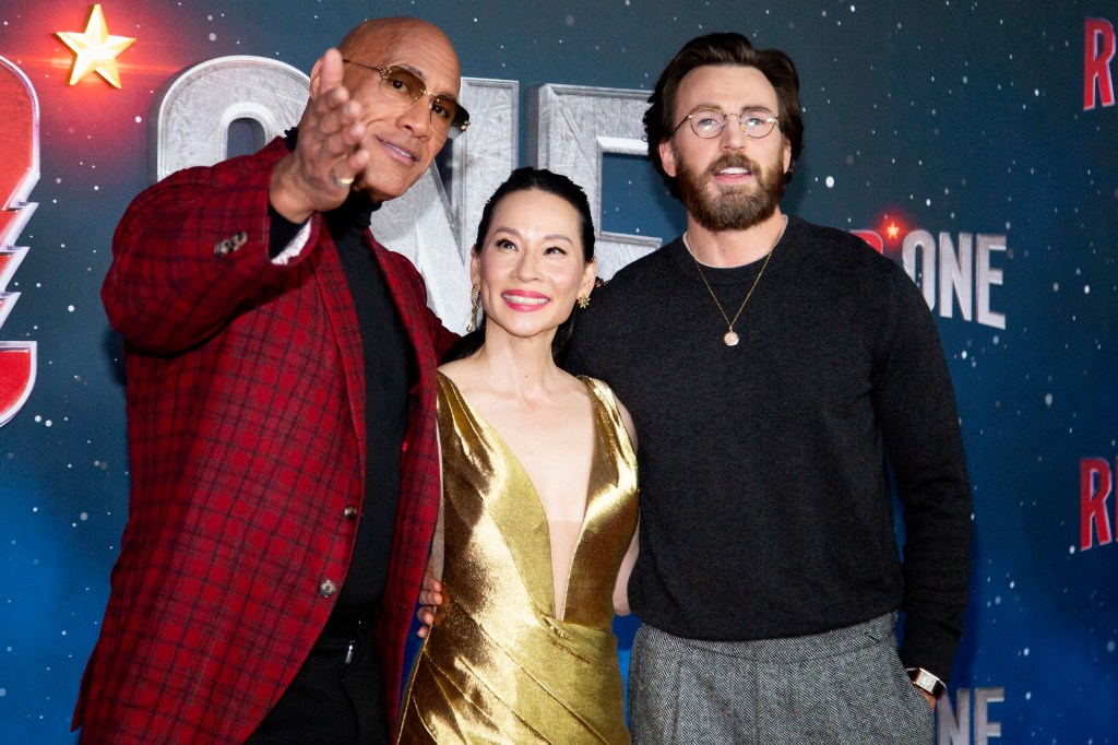 Dwayne Johnson, Lucy Liu, and Chris Evans posing for a photo at the 'Red One' New York Premiere at Alice Tully Hall, Lincoln Center