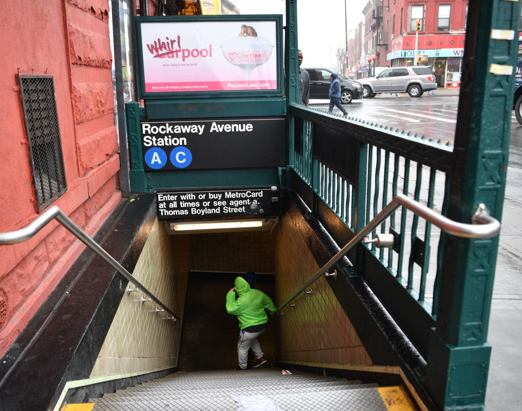 MTA workers painting yellow lines on the subway platform during rush hour at Rockaway Avenue station, Bed-Stuy, with passengers walking and leaving footprints.