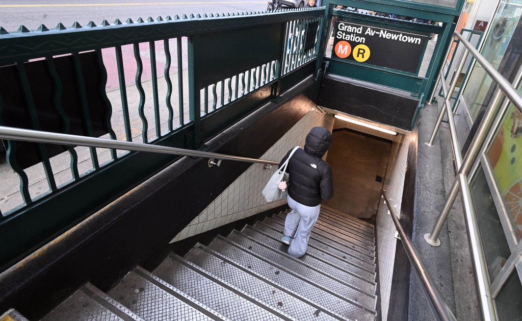 Person walking up the stairs to the entrance of the Grand Ave.-Newtown subway station on Queens Blvd, New York, with a new scent diffuser installed