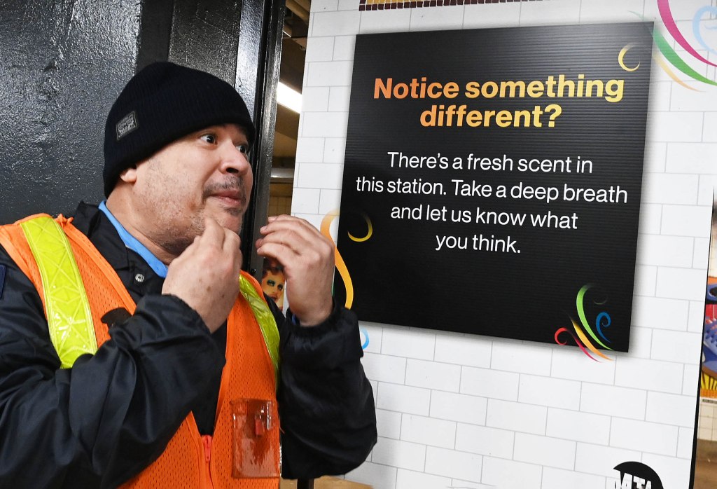 MTA security guard Nelson Victor, in a black hat and orange vest, enjoying the new pleasant aroma at the Grand Ave.-Newtown subway station in Queens, New York