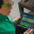 A person is holding a tablet displaying colorful charts and graphs.