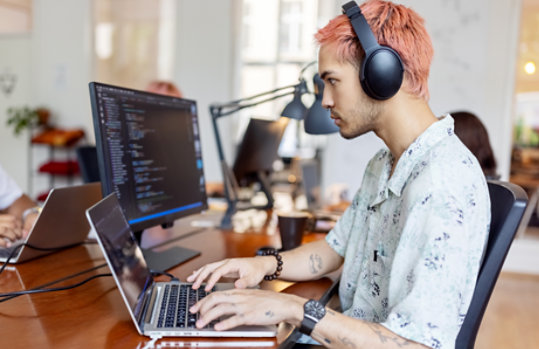 A man in headphones works with his laptop in the office.