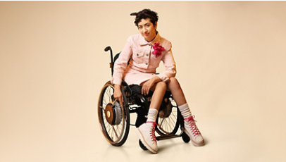 A woman wearing a stylish pink outfit in a wheelchair.