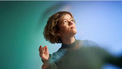 Woman looking up and off-camera amidst of vibrant blur of green and blue.