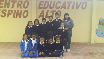 A group of children in uniforms pose with an adult in athletic clothing.