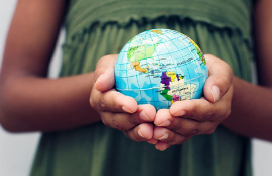 A close-up photo of a woman holding a small globe with North and South America visible.