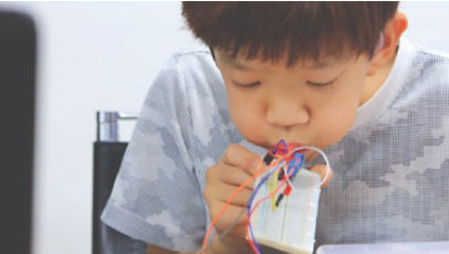 A child blows into a digital device.