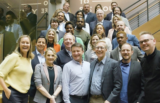 A group of business professionals pose on a stairwell for a group shot.