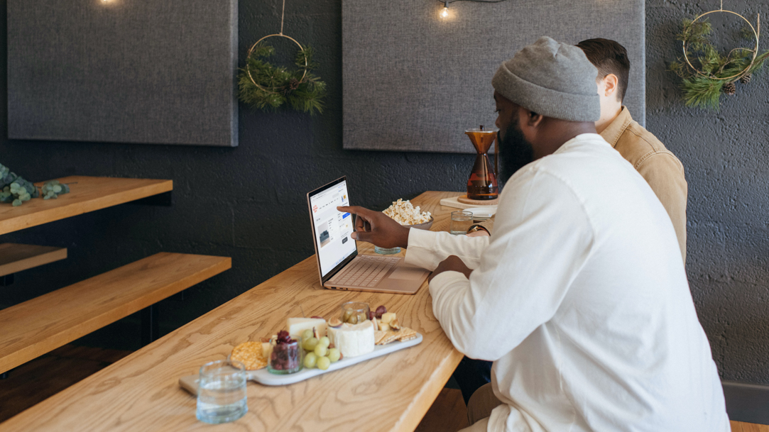 A man using a laptop while sitting at a table at a cafe