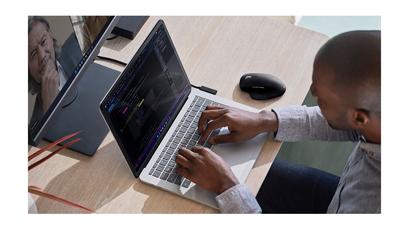 A man works on a Surface device at his desk