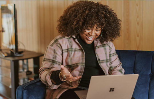 A person sitting on a couch holding a Surface device