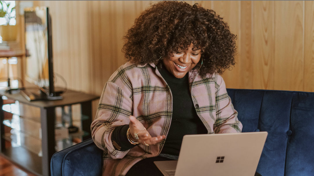 A person sitting on a couch holding a Surface device