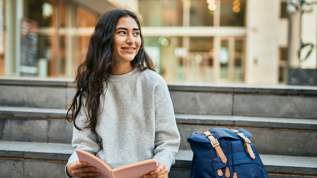 A student smiling reading a book at a university