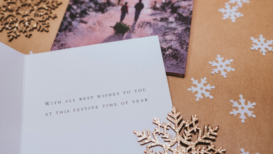 A white greeting card on a brown background and cut out paper snowflakes