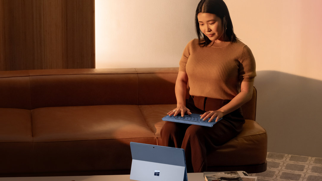 A woman typing on a Surface Pro 11ᵗʰ Edition using a detached Surface Pro Flex Keyboard