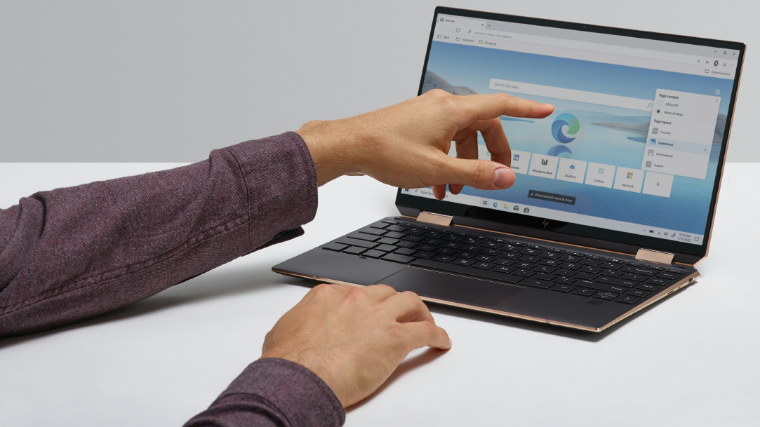 A woman’s hand pointing to a laptop with Microsoft Edge on the screen