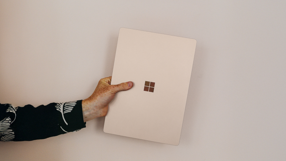 An image of someone holding a Surface laptop in their hand