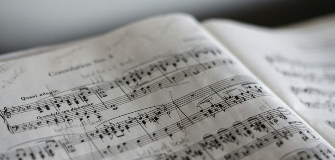 An open book of sheet music with notes written in pencil