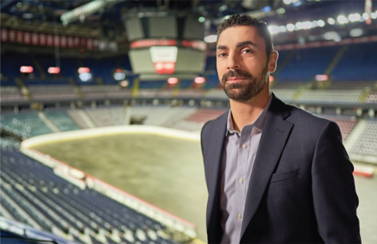 Ziad Mehio is standing in a stadium wearing a navy sports coat.