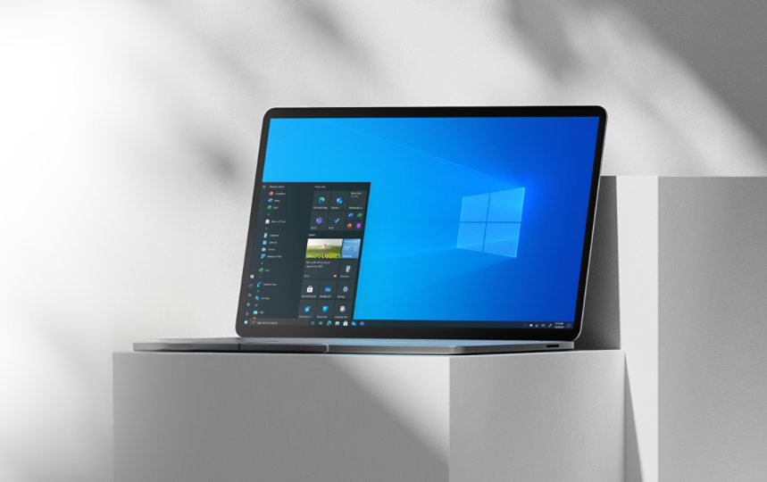 Laptop on a white pillar open to Windows 10 home screen.
