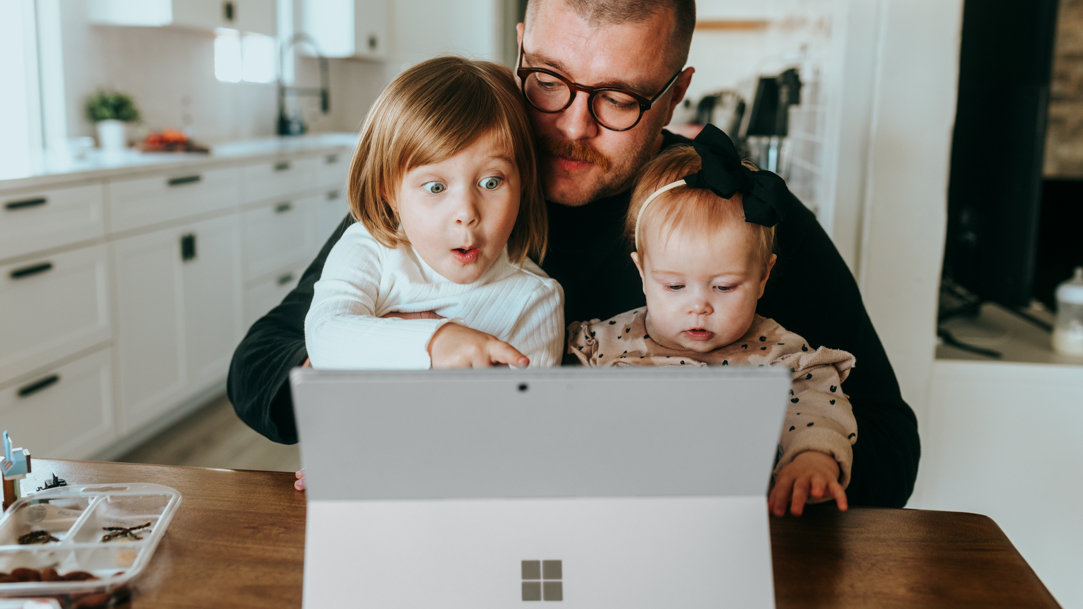 Father looking at photos on tablet with two small children