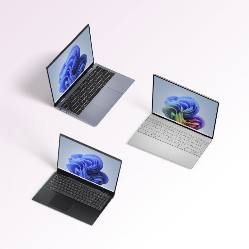 An array of open Microsoft laptops, one with the rainbow bloom and two with the blue bloom on screen.