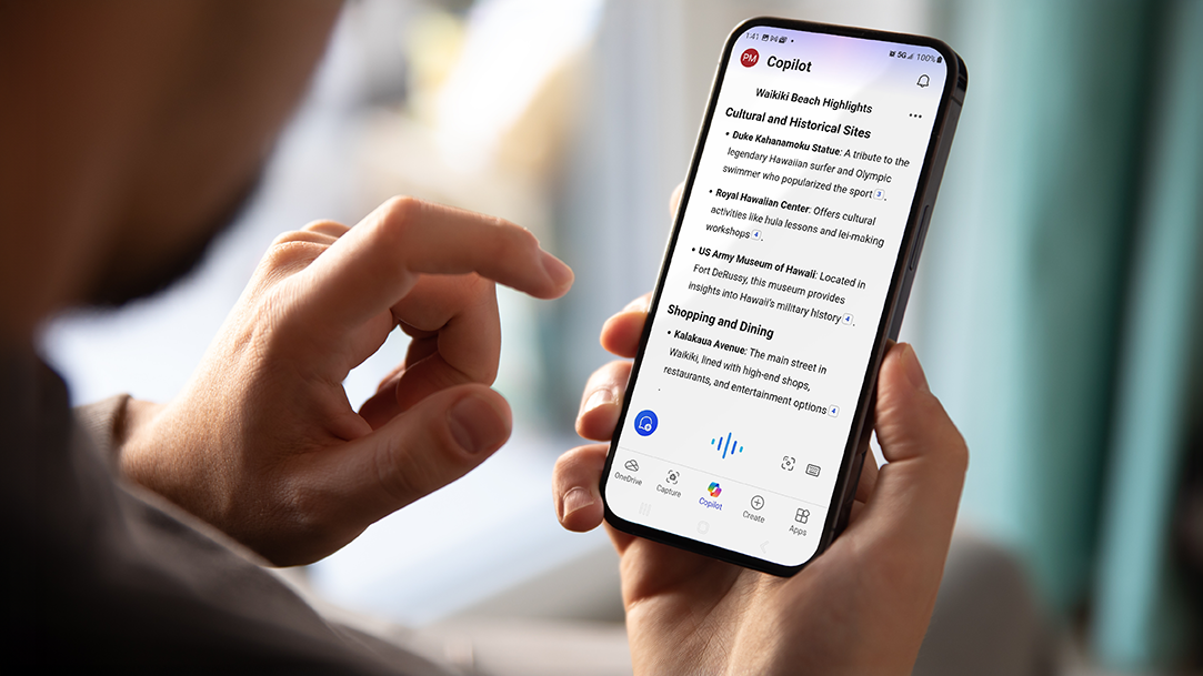 Hand holding a mobile phone and using Copilot