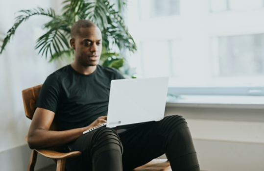 Man sitting in a wooden chair using his Windows laptop