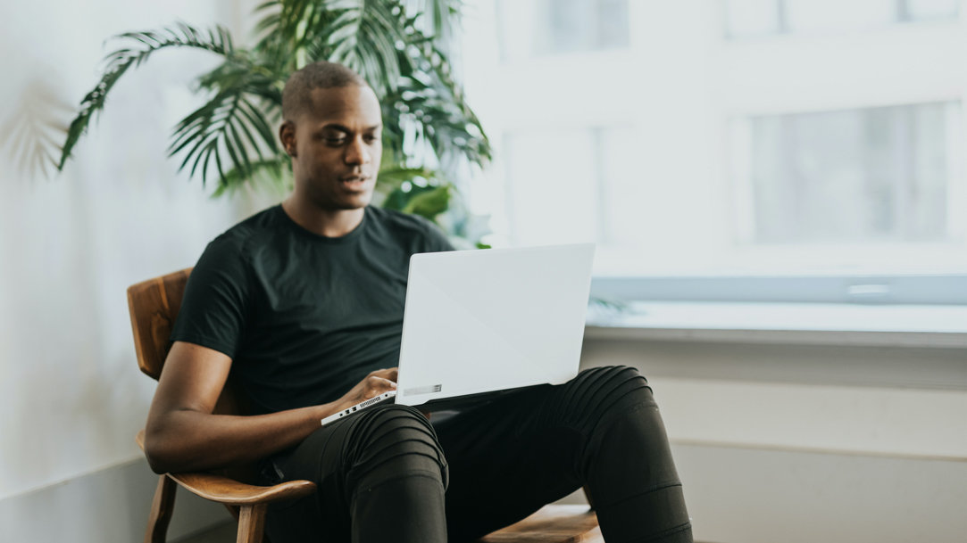 Man sitting in a wooden chair using his Windows laptop